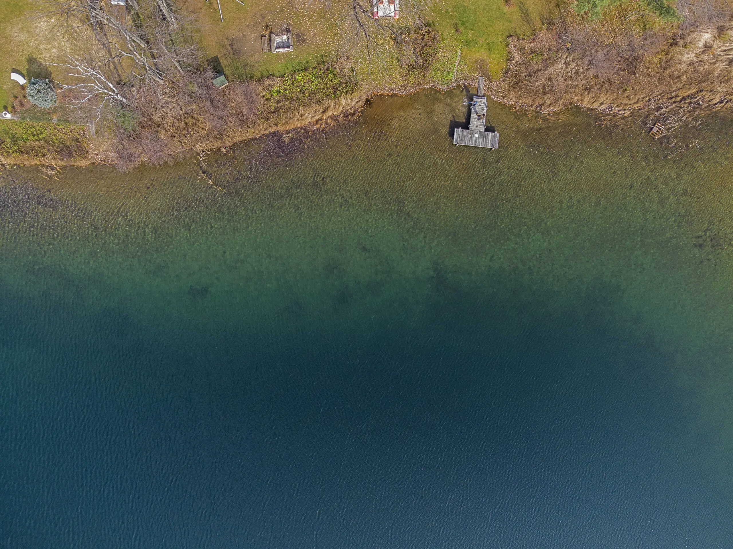 vue aérienne spectaculaire d'un lac mythique de Lanaudière en automne. Les couleurs éclatantes évoquent des teintes caribéennes, offrant un contraste saisissant avec le paysage environnant.