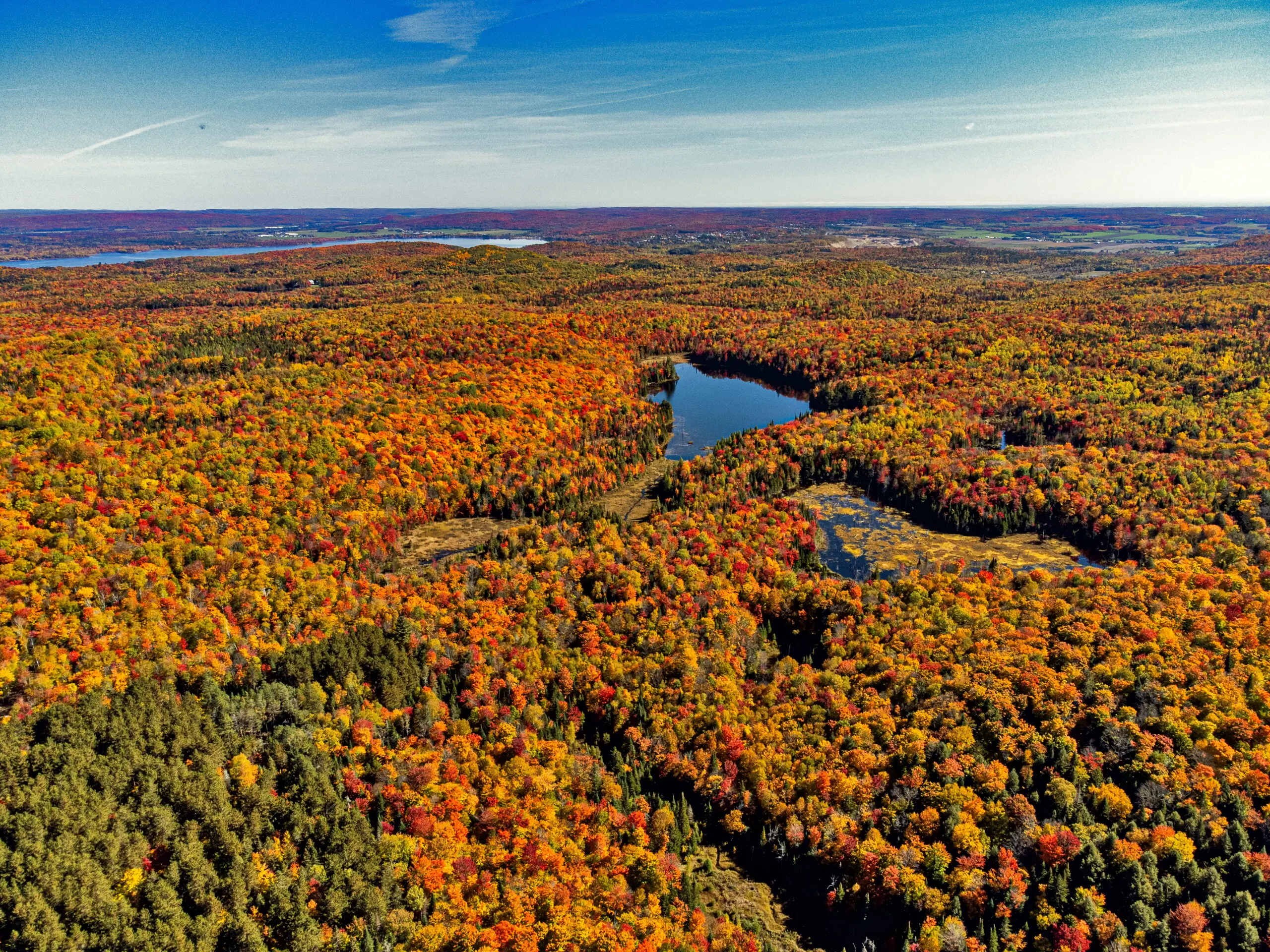 vue aérienne du lac Ida aux Jardins de l'Écoumène en automne, avec des couleurs vibrantes et chaleureuses capturées par drone.